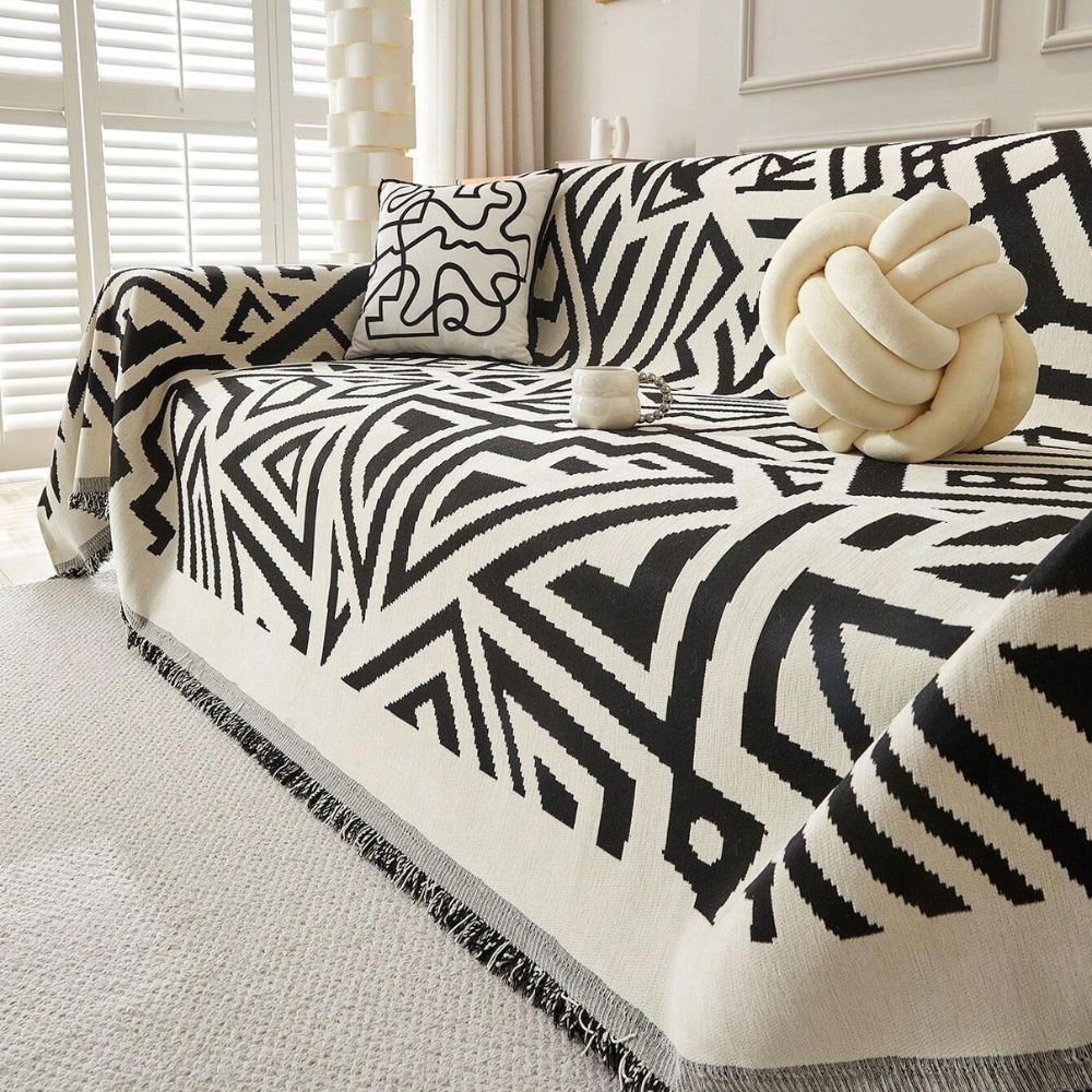 Sofa with a black and white patterned throw blanket and decorative knot pillow.